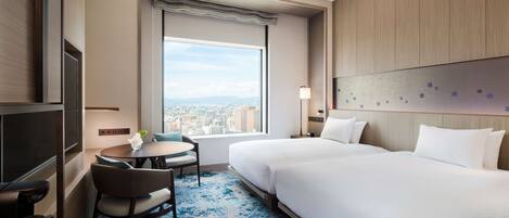 A hotel room with two beds, a TV, a small table with a chair, and a large window with a city view.