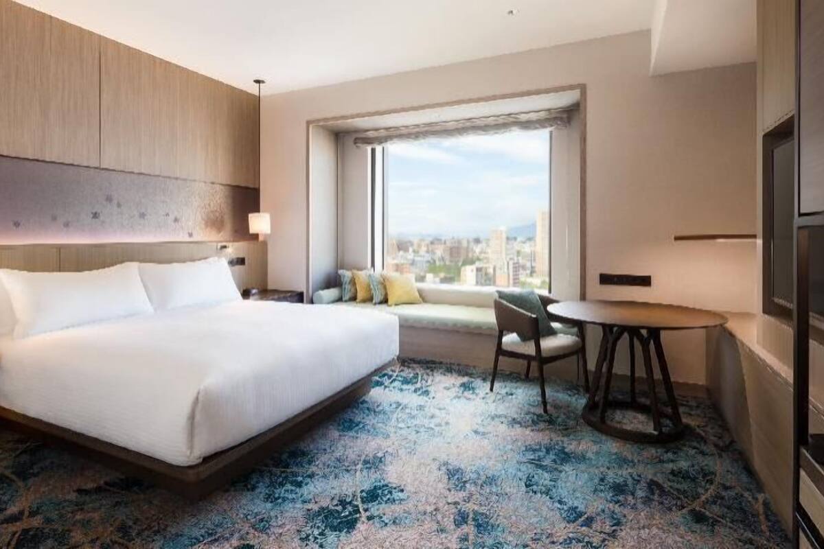 Una habitación de hotel con una cama grande, un sofá, una mesita y un televisor.