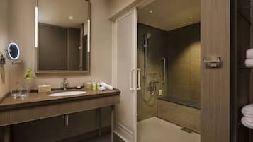 A modern bathroom with a large mirror, a sink, and a walk-in shower.