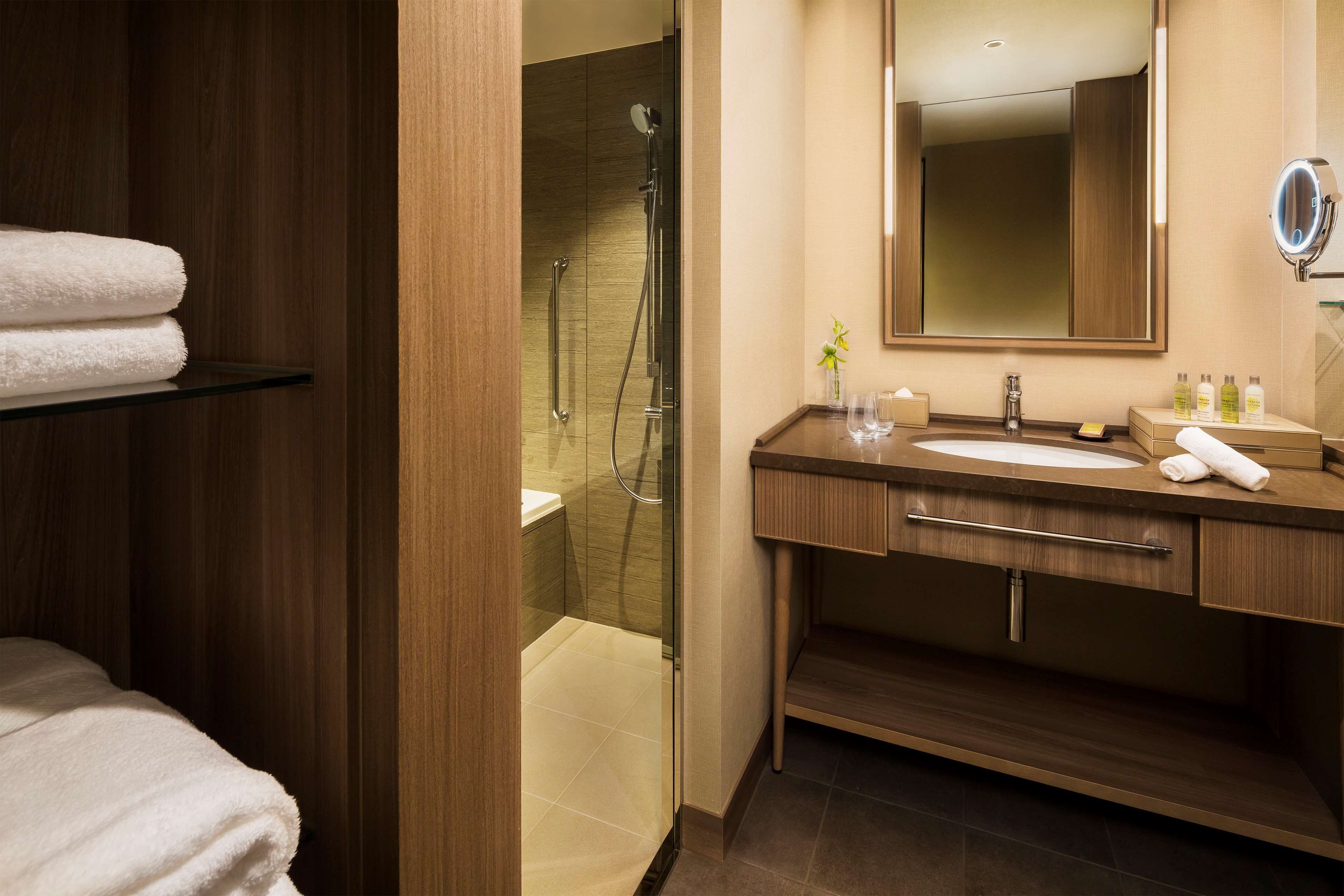 A modern bathroom with a glass-enclosed shower, a wooden vanity with a sink, and a mirror.