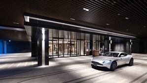 Fachada moderna de un edificio con un coche deportivo blanco estacionado frente a él.