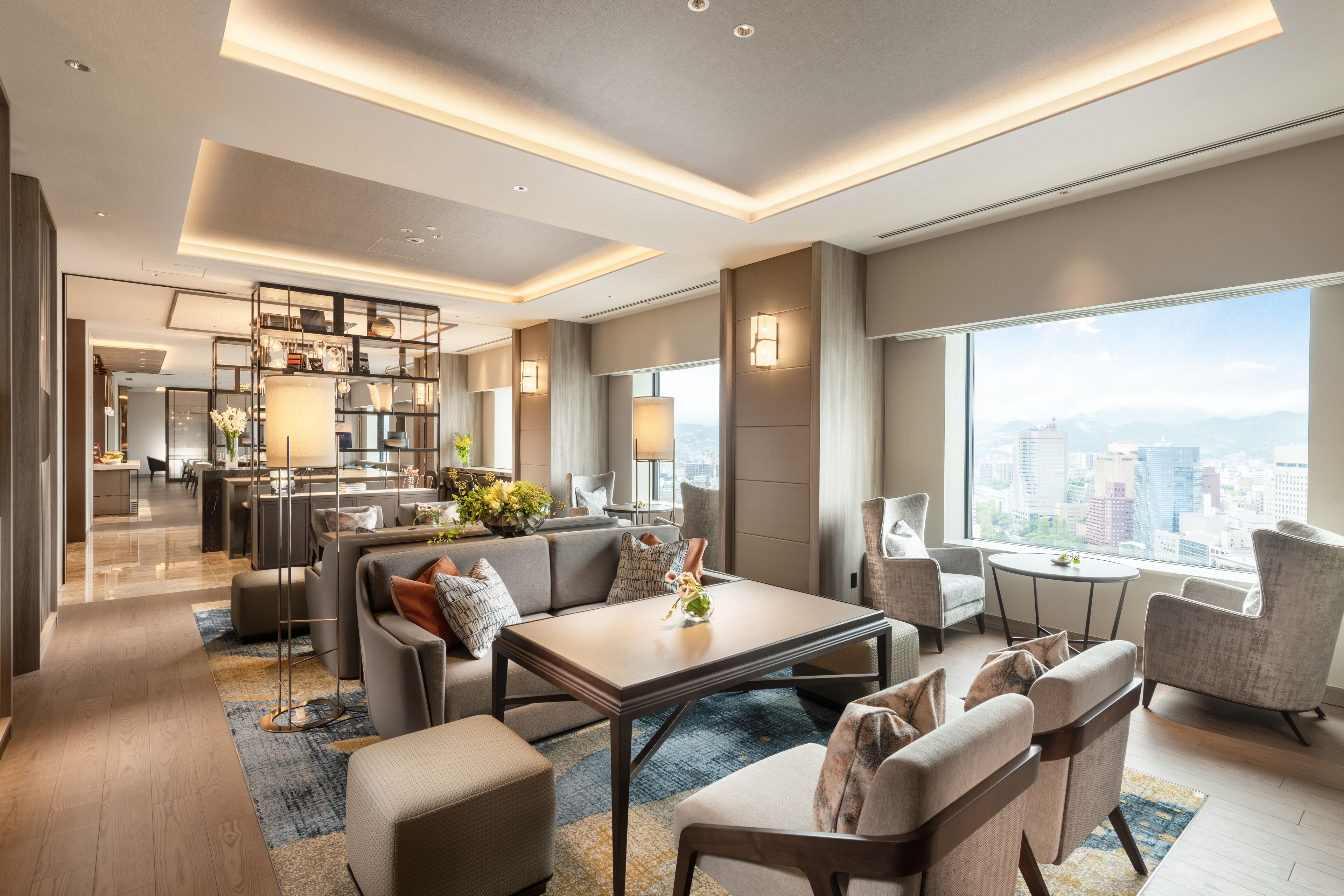 Une chambre d’hôtel moderne dotée d’un espace salon, d’un coin repas et offrant une vue sur la ville.