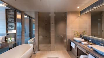 Une salle de bain moderne dotée d’une grande baignoire, d’une douche à l’italienne et d’un meuble-lavabo avec un grand miroir.