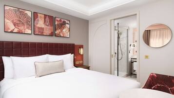 Une chambre d’hôtel avec un grand lit, une tête de lit rouge, un miroir rond et des œuvres d’art accrochées au mur.