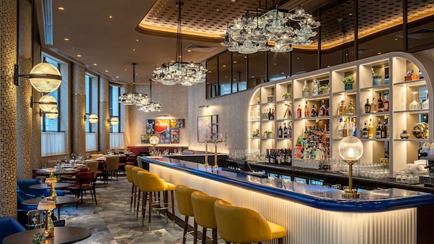 A bar area with a curved counter, yellow bar stools, and a variety of bottles and glasses. - Lost Property St. Paul's London, Curio Collection By Hilton (London)