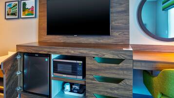 A modern entertainment unit with a flat-screen TV, a microwave, and storage drawers.