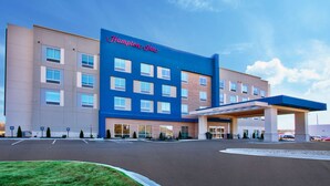 A Hampton Inn hotel with a blue facade, a covered entrance, and a parking lot. - Hampton Inn By Hilton Paris (Paris)