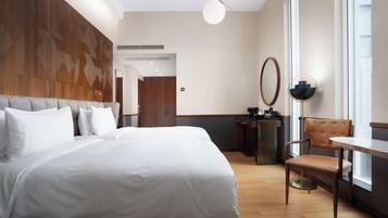 Une chambre d’hôtel moderne dotée d’un grand lit, d’une table à manger, d’une chaise, d’un miroir et offrant une vue sur l’extérieur.