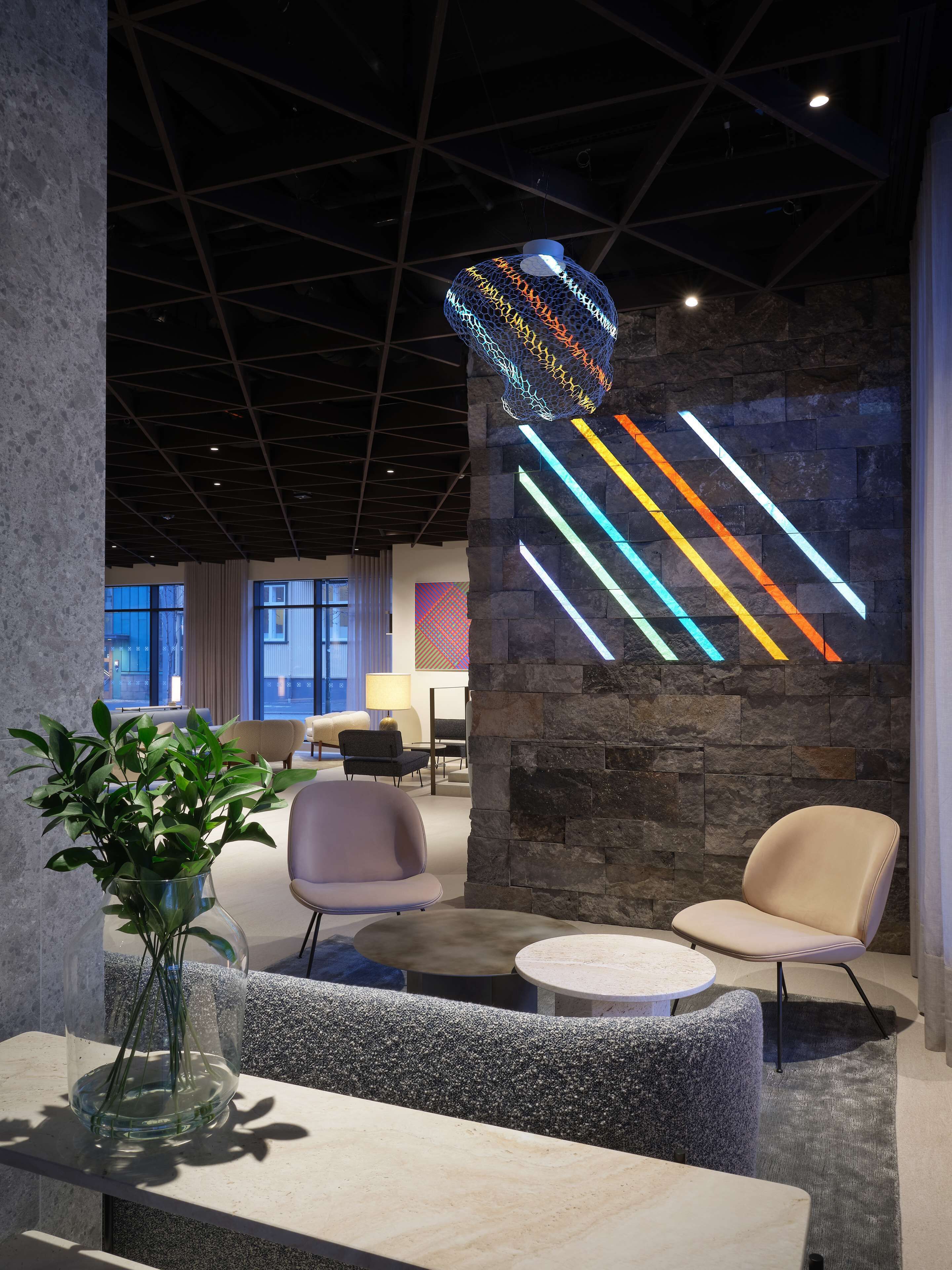 A modern interior with a stone wall, colorful light installation, and seating area.