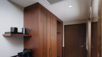 A compact kitchenette with a countertop, a coffee machine, and a small shelf.