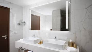 A modern bathroom with two sinks, a large mirror, and a wooden bench.