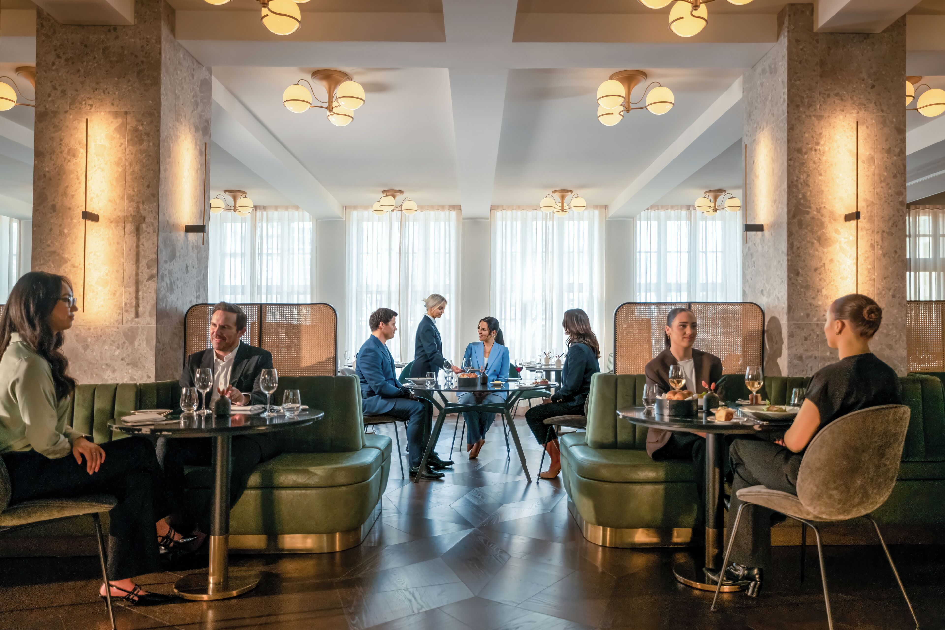 A modern dining area with round tables and green upholstered seating.