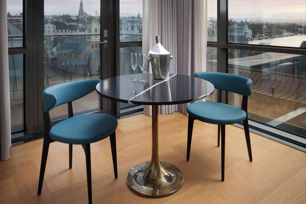 Un comedor moderno con una mesa redonda, dos sillas azules y una lámpara colgante original.
