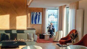 A modern living room with a fireplace, comfortable seating, and a large window offering a view of buildings.