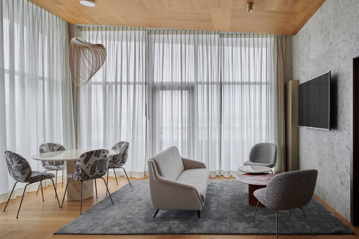 Una sala de estar moderna con un sofá, sillas, una mesa de centro y un televisor montado en la pared.