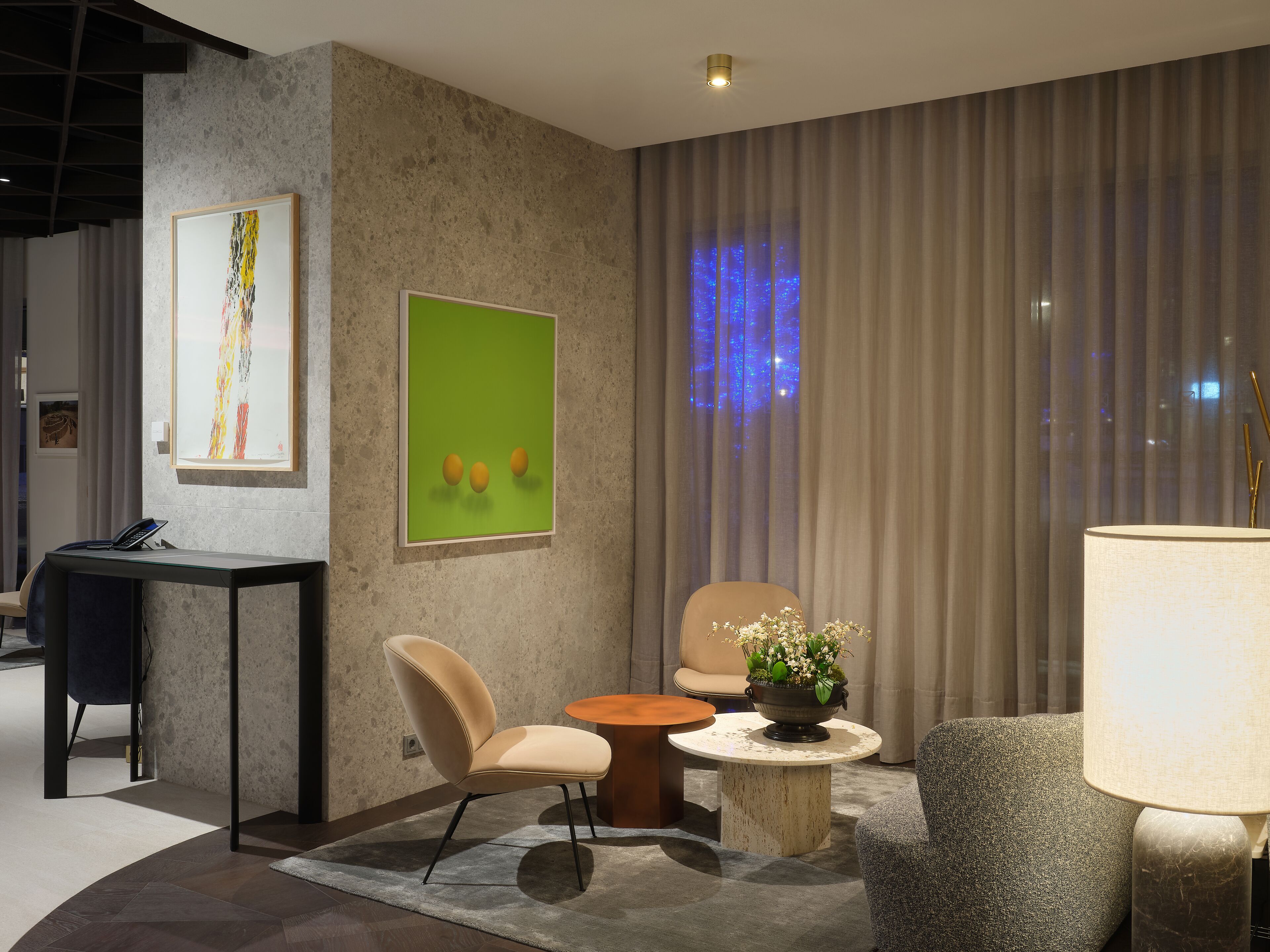 Un moderno vestíbulo de hotel con una recepción, zona de estar y obras de arte en las paredes.