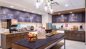 A modern kitchen area with a central island, various appliances, and a chalkboard wall with food-related drawings.