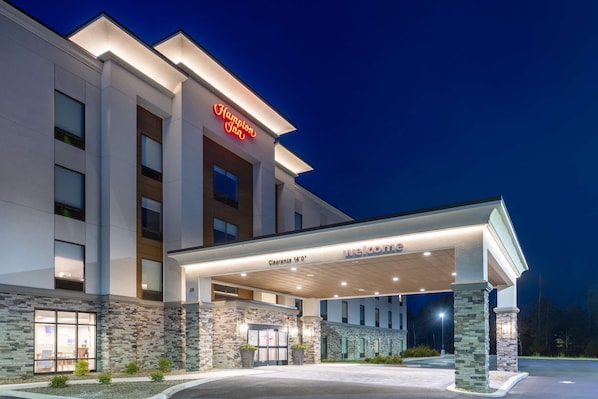 A Hampton Inn hotel with a modern facade, a clear entrance, and a welcoming gas station.