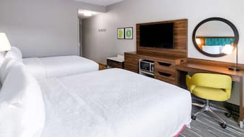 A hotel room with two beds, a desk, a chair, a TV, and a mirror.