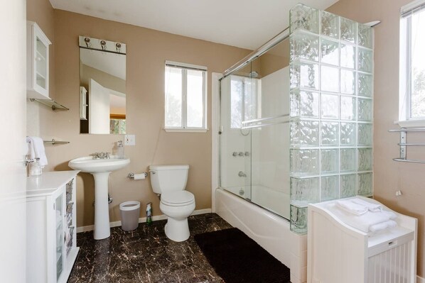 Un baño con cabina de ducha de vidrio, un lavamanos blanco y un inodoro.