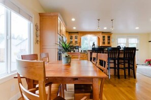 Una cocina amplia con armarios de madera, una mesa de comedor con sillas y vistas al jardín trasero a través de un ventanal.