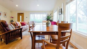 A dining area with a wooden table and chairs, a sofa, and a potted plant.