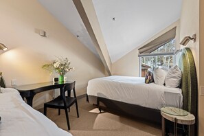Enjoy a spacious and airy feel in this room with a high ceiling, featuring a bed, bedside table, and chair.