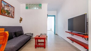 A living room with a grey sofa, a red table, a TV on a red stand, and a painting on the wall. - Apartment El Cotarro B  (Vejer de la Frontera)