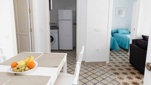 Spazio abitativo compatto con zona pranzo, angolo cottura e camera da letto con un letto e biancheria azzurra.