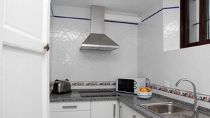 Una cucina con mobili bianchi, un lavello in acciaio inossidabile, un forno a microonde e un tostapane.