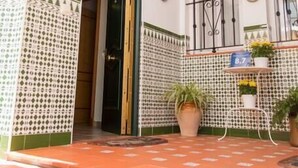 A courtyard with a tiled floor, a door leading inside, a hanging light fixture, and potted plants. - Apartment El Cotarro A  (Vejer de la Frontera)