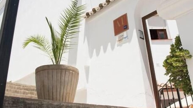 A white building with a small entrance, a potted plant, and a visible door. - Apartment El Cotarro A  (Vejer de la Frontera)