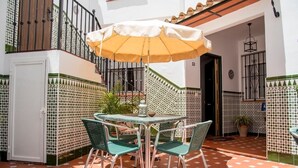 An outdoor patio with a table and chairs, a yellow umbrella, and patterned walls. - Apartamento El Cotarro B (Vejer de la Frontera)