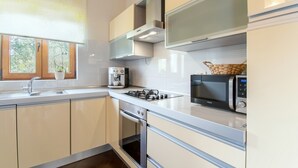 Een moderne keuken met een roestvrijstalen fornuis, een magnetron en een koffieapparaat.