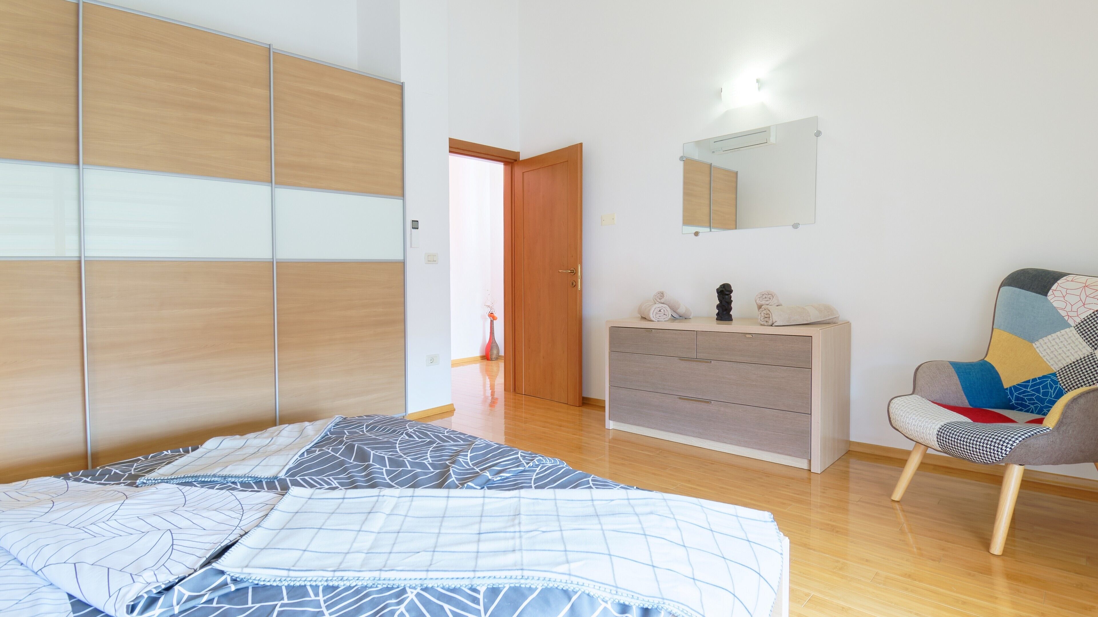 A bedroom with a bed, a dresser, a chair, and a wardrobe.