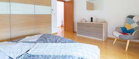 A bedroom with a bed, a dresser, a chair, and a wardrobe.