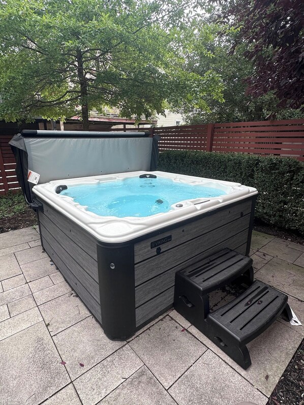 A hot tub with a cover, a step for access, and a wooden bench beside it.