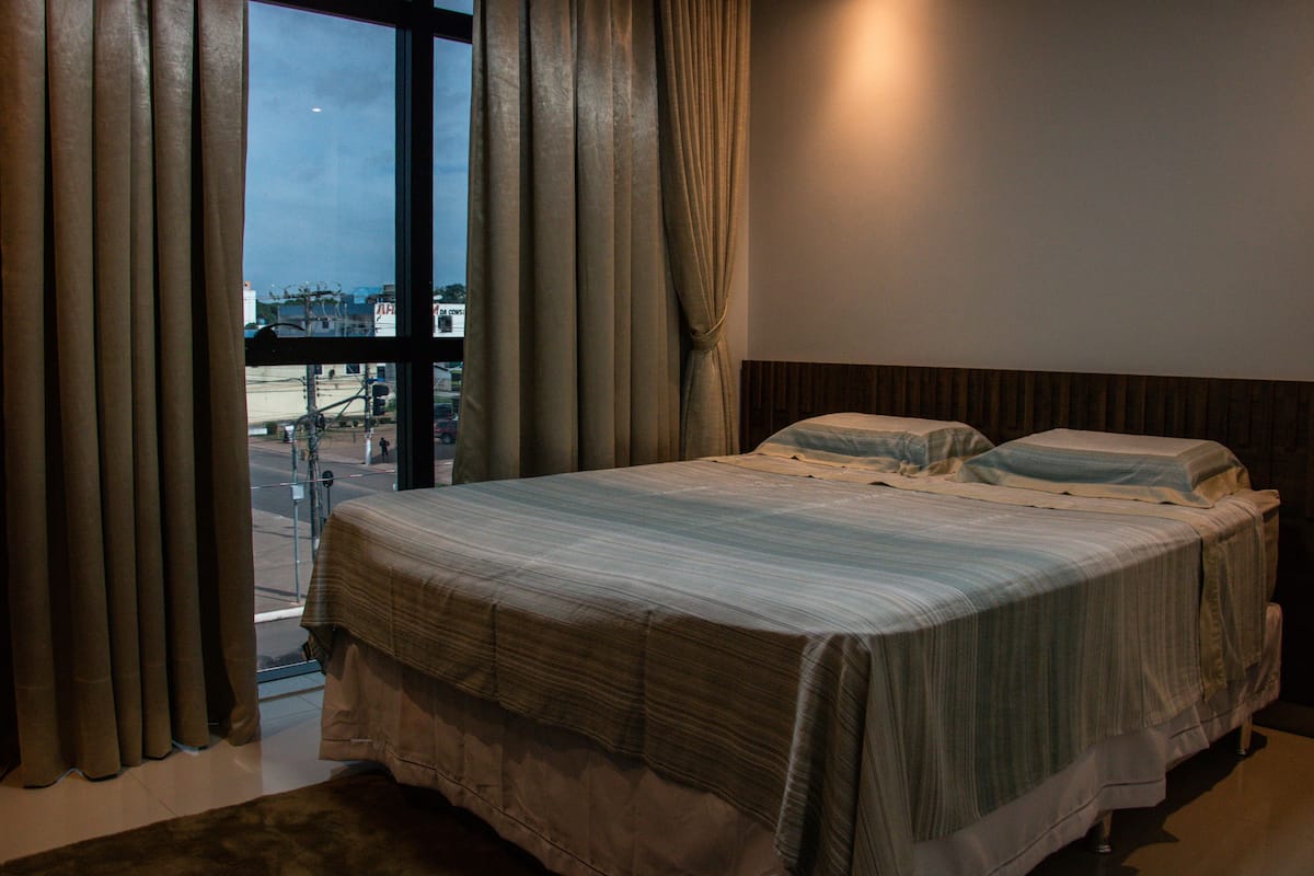 Habitación de hotel con una cama grande, cortinas y vistas al exterior.