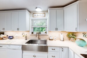 Enjoy cooking in this well-lit kitchen with a stainless steel sink, dishwasher, and white cabinetry.