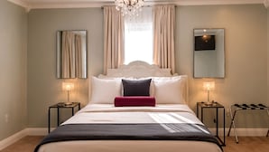 Una camera da letto con un letto, due comodini, un lampadario e un grande specchio.