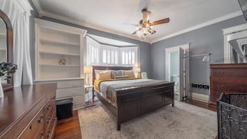 Un dormitorio con una cama grande, ventilador de techo y vista al baño.