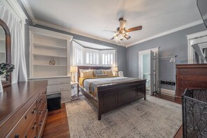 Une chambre avec un grand lit, un ventilateur de plafond et une vue sur la salle de bain.