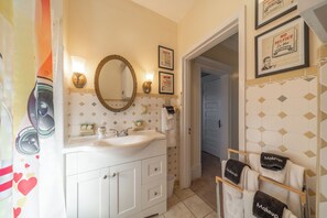 Une salle de bain avec un lavabo blanc, un miroir et un porte-serviettes sur lequel sont disposées des serviettes étiquetées « Maquillage ».