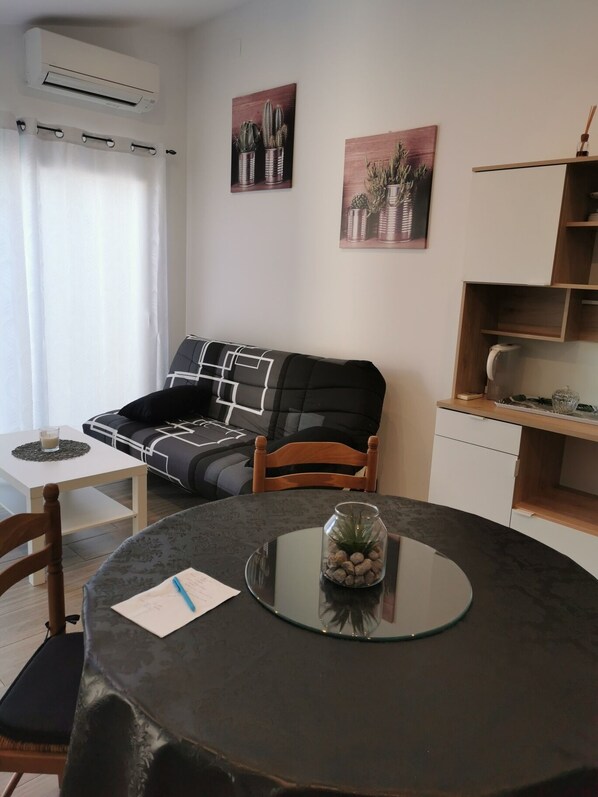 Un salon chaleureux avec une table ronde, un canapé noir et blanc et deux tableaux accrochés au mur.