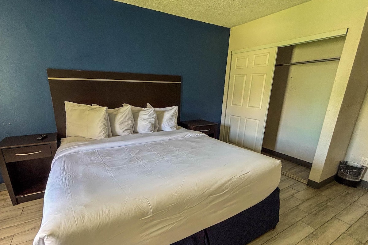 A neatly made bed with white bedding in a room with blue walls and wooden flooring.