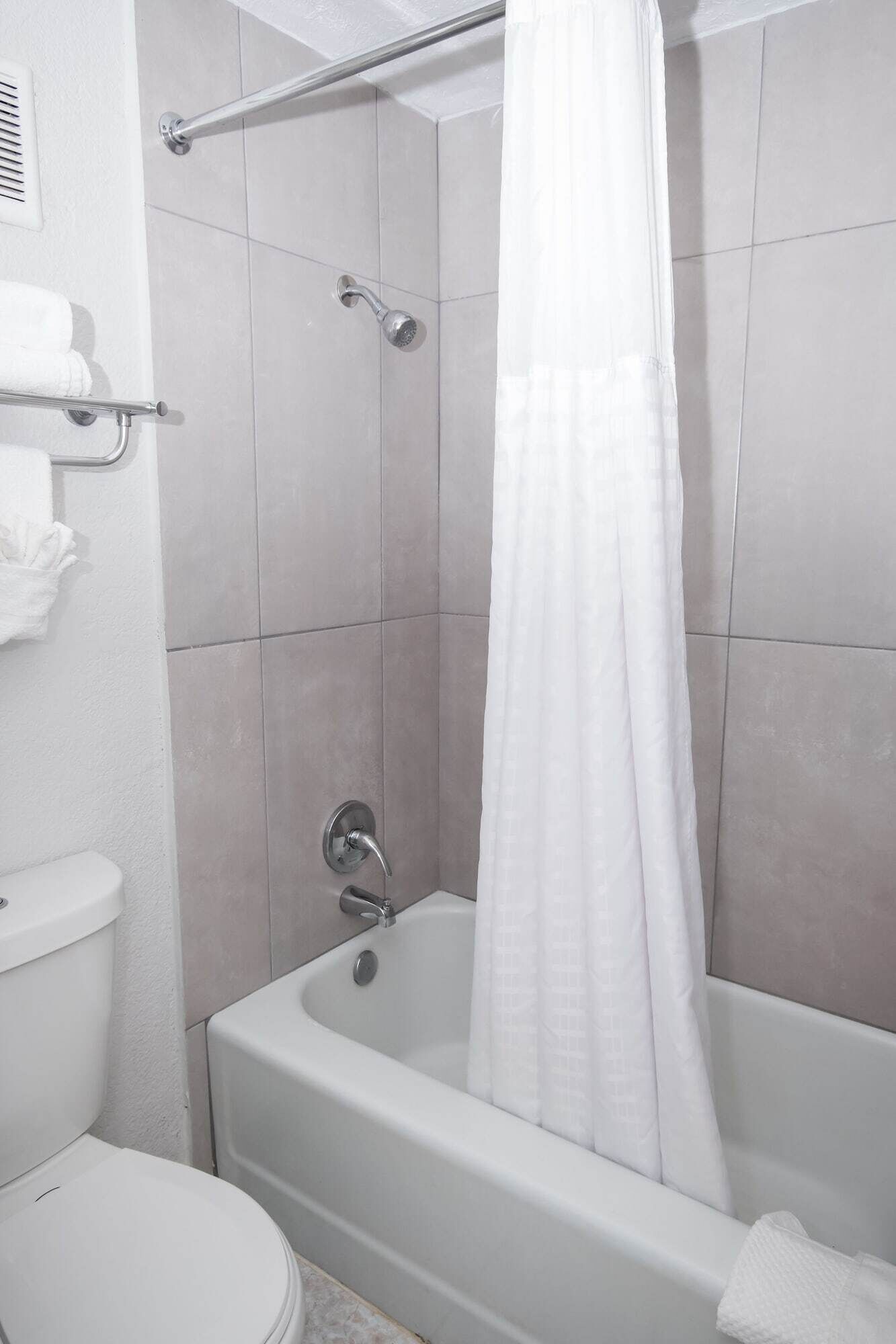 A bathroom with a bathtub, toilet, and shower curtain.