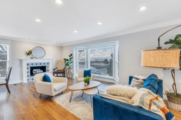 A living room with a fireplace, a blue sofa, a white armchair, and a round coffee table.