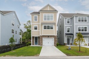 Une rangée de maisons de ville avec un garage central, une pelouse devant et un ciel dégagé.