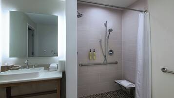 A bathroom with a sink, mirror, shower, and toilet.