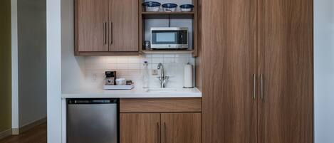 Una cocina moderna con gabinetes de madera, lavavajillas de acero inoxidable, microondas y fregadero.